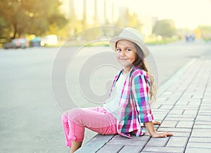 Happy smiling little girl child wearing a checkered pink shirt and hat