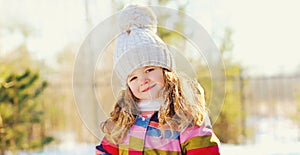 Happy smiling little girl child in winter over a snowy background