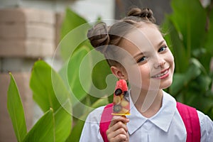 Happy smiling little girl with fruit ice cream. Portrait of cute kid with blue eyes on city background