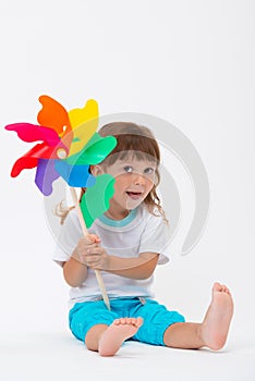 Happy smiling little girl holding a colorful toy pinwheel windmill isolated on white background