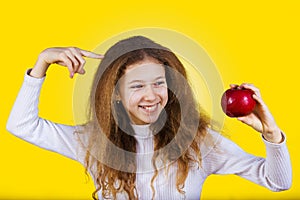 Happy, smiling little girl holding an red apple, pointing with f