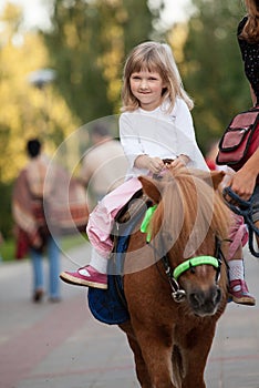 Happy smiling little girl on a pony