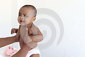 Happy smiling little six month crawling African American baby playing and laughing in hands of her mother, sweet kid plays with