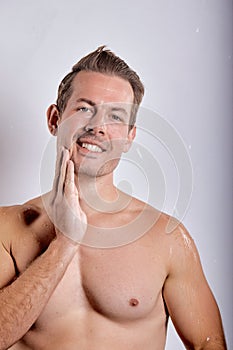 Happy smiling macho man guy holding hands touch perfect skin on face, posing