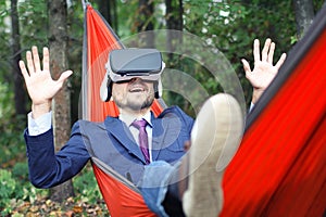 Happy smiling man in casual wear uses vr glasses, resting in a h