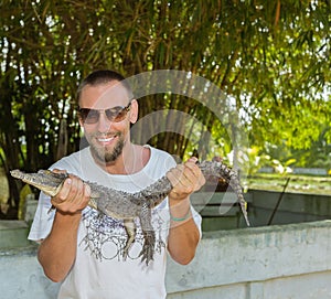 Happy smiling man holding a crocodile