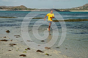 Happy smiling man with perfect body running from sea waves splashing water. Vacations on sea shore concept