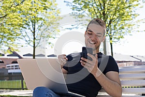 Happy smiling man reading good news in sms on mobile phone