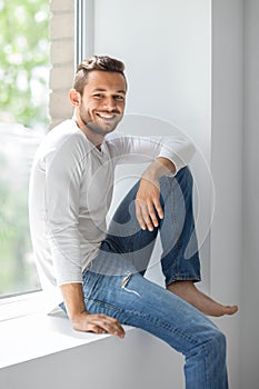 Happy smiling man relaxing on window sill