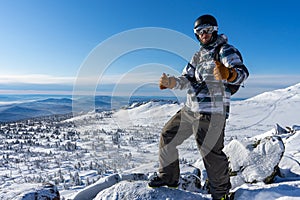 Happy Smiling man in skiing or winter equipment shows thumbs up. Warm jacket, brown gloves, ski goggles, helmet
