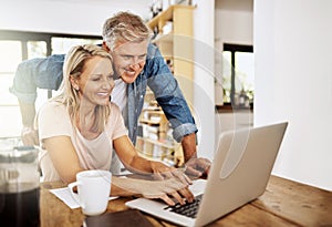 Happy, smiling and mature couple using a laptop together at home. Charming husband assisting wife with online work on