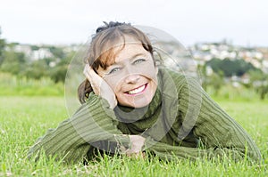 Happy smiling mature woman laying on grass