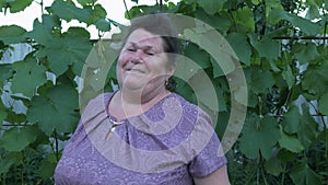 Happy smiling mature woman singing to the camera. Old retired female sings on green background. Portrait of happy pensioner woman.