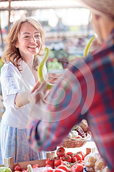 Happy smiling mid adult woman buying fresh organic vegetables in an open air marketplace