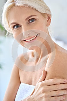 Happy smiling mid age woman looking at camera touching embracing shoulder.