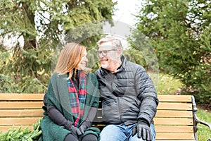 Happy smiling middle age couple sitting on a park bench in winter