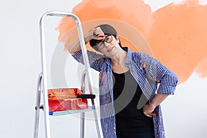 Happy smiling middle-aged woman painting interior wall of new house. Redecoration, renovation, apartment repair and