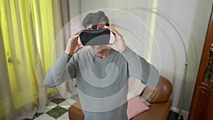 Happy smiling Middle Eastern man in VR headset standing in living room at home. Portrait of excited joyful handsome guy