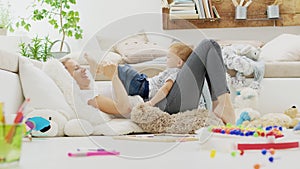 Happy and smiling mom cuddles her son child baby playing with him, lying at home between pillows, healthy and cared for growth photo