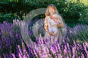 Happy smiling mother with baby girl and lavender flowers