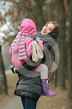 Happy smiling mother with a child daughter in her arms posing at spring park path outdoors