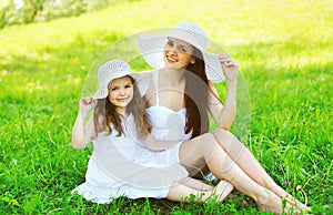 Happy smiling mother and daughter child wearing white straw hats