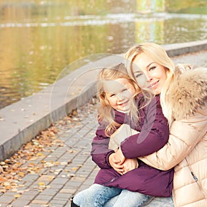 Happy smiling mother and daughter outdoor near lake.