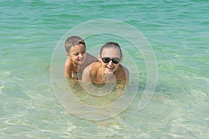 Happy smiling mother and her son playing and running on the beach. Concept of friendly family - Image