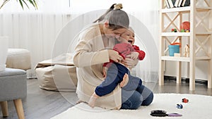 Happy smiling mother hugging her baby son and tickling him. Baby development, family playing games, having fun together,