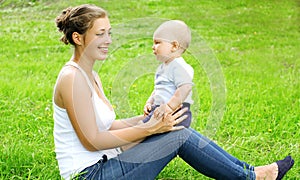 Happy smiling mother and son child sitting on the grass