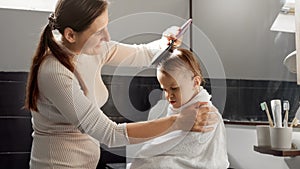 Happy smiling mother wiping her baby son in bath with towel and combing his hair. Concept of parenting, happiness and child