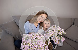 Happy smiling mothers with her son with a large bouquet of pink flowers