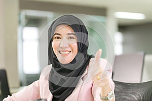 Happy smiling muslim lady in hijab showing thumb up, Cheerful muslim business woman giving thumbs up in the office
