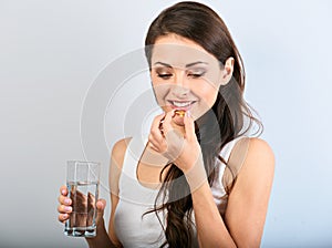 Happy smiling natural positive woman holding the vitamin E capsule in the hand and glass of pure water. Closeup