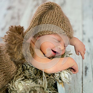 Happy smiling newborn baby boy in knitted hat and pants, soundly