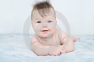 Happy smiling newborn baby portrait cute and adorable in her three month, infant child with blue eyes lying on bed looking