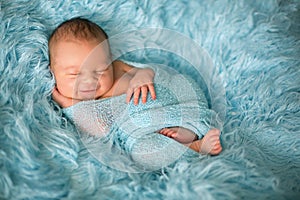 Happy smiling newborn baby in wrap, sleeping happily in cozy fur