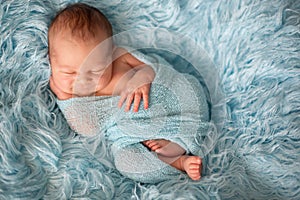 Happy smiling newborn baby in wrap, sleeping happily in cozy fur