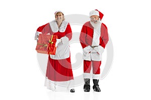 Happy smiling old man in Santa Claus costume and cute woman, missis Claus with gift boxes isolated on white background.