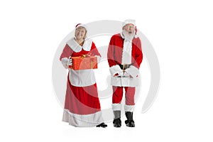 Happy smiling old man in Santa Claus costume and cute woman, missis Claus with gift boxes isolated on white background.