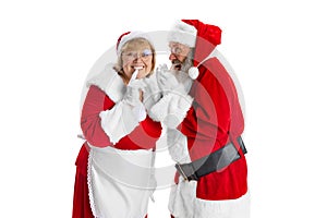 Happy smiling old man in Santa Claus costume and cute woman, missis Claus keeping secrets isolated on white background.