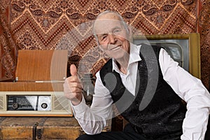 Happy smiling old man in white shirt holds thumb up and looking at the camera