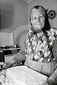 A Happy, Smiling Old woman, Grandmother, Senior is baking, cooking in the kitchen at a cozy home. Middle european culture.