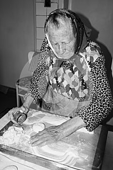 A Happy, Smiling Old woman, Grandmother, Senior is baking, cooking in the kitchen at a cozy home. Middle european culture.