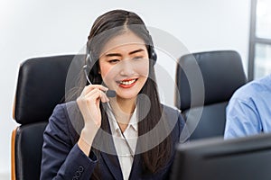 Happy smiling operator asian woman customer service agent with headsets working on computer in a call center, talking with