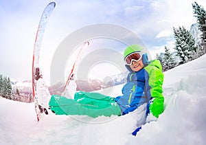 Happy smiling portrait of boy with ski sit in snow