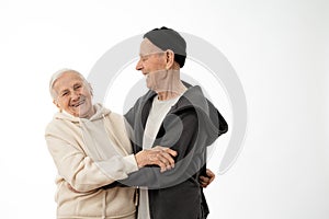 Happy smiling positive pencioner couple in hoodies hugging, stylish old man and woman isolated over white background