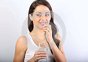 Happy smiling positive woman eating the pill and holding the glass of water in the hand on white background. Closeup portrait