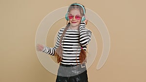 Happy smiling preteen child girl listening music dancing disco fooling around having fun indoors