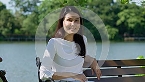 Happy smiling pretty Asian woman with a smile on her face looking at the camera in broad daylight in the park, natural sunlight,